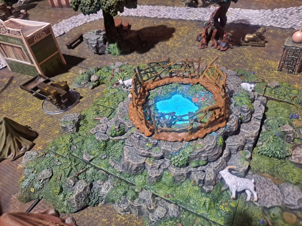 A round glowing and swirling portal is surrounded by a gate and stones on a small grassy hill with a curious goat nearby.